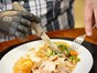 Mann schneidet Essen mit Hilfe von Prothese und Messer